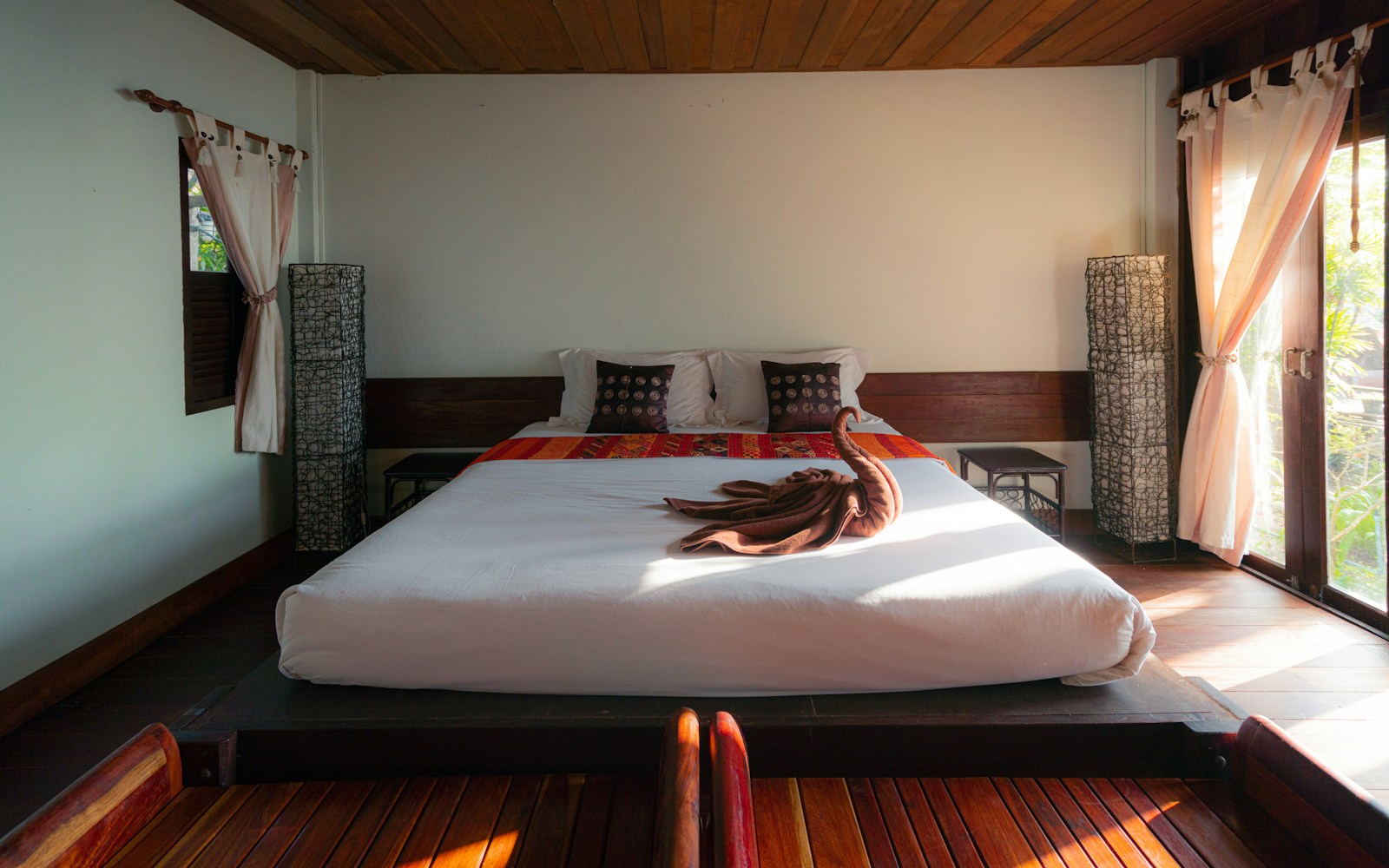 Quiet boutique guest room with white linen, warm wood and garden views